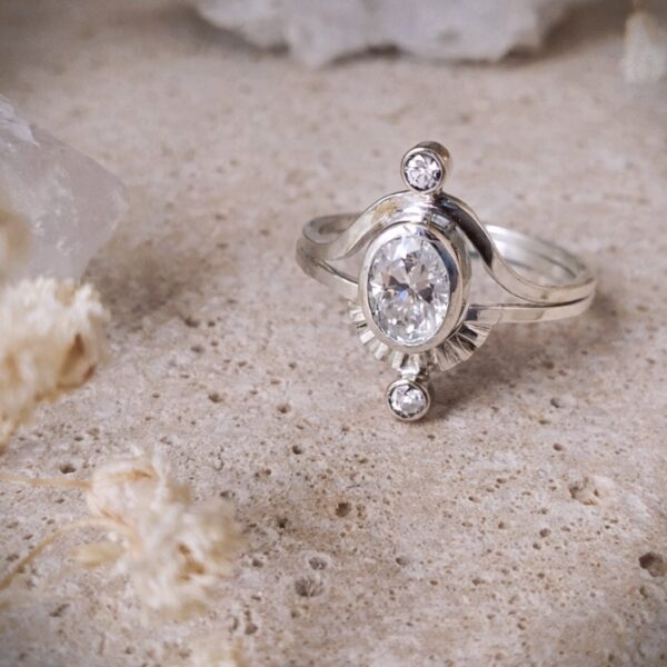 Two-band Saturn ring set in sterling silver with moissanite center stone and moissanite accents.