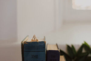 Gold Dauntless Heart ring featuring a pear-shaped aquamarine, displayed on books with soft lighting.
