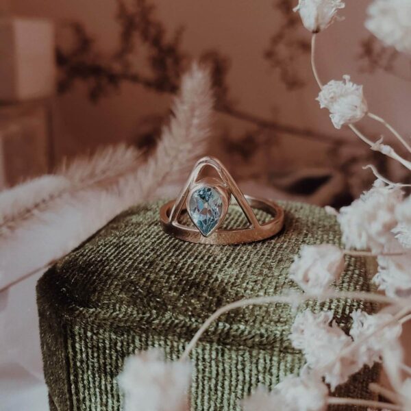 Dauntless Heart Aquamarine Ring in 14k gold on green velvet ring box with dried baby's breath, foliage, and crystal accents