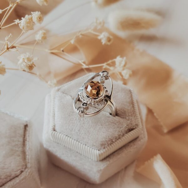 Jupiter ring set in sterling silver featuring an 8mm citrine center stone with moissanite accents, displayed in a cream velvet ring box.