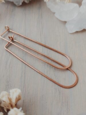 Sterling silver long oval threader hoop earrings displayed flat with dried florals and a crystal in the background.