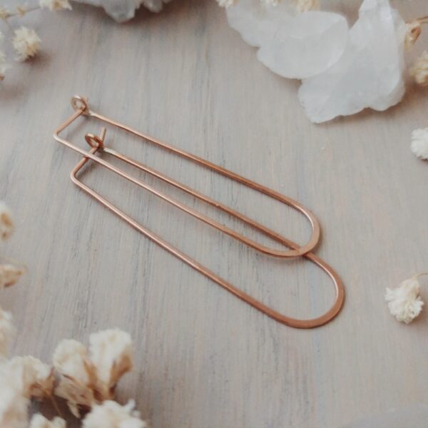 Sterling silver long oval threader hoop earrings displayed flat with dried florals and a crystal in the background.